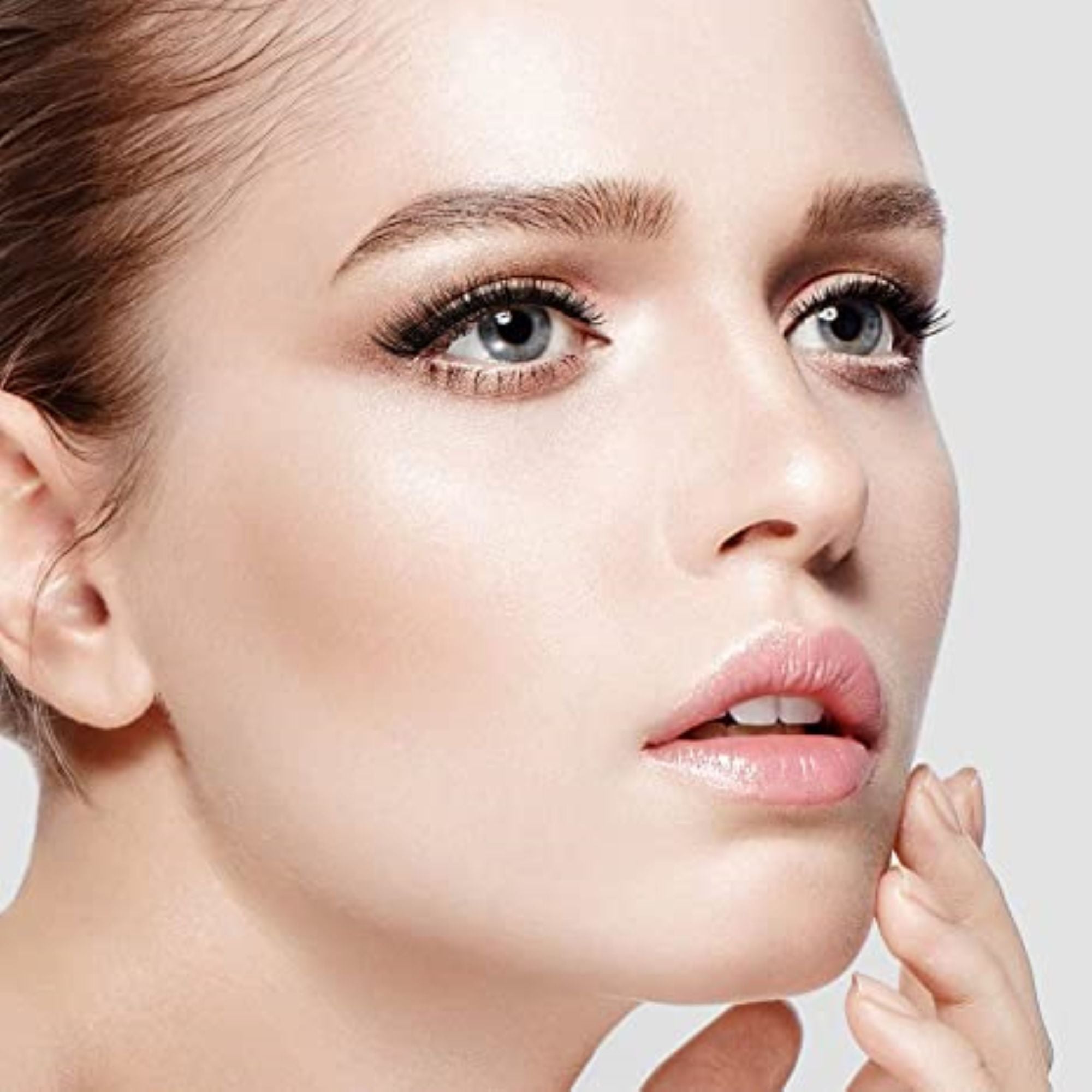 Close-up of a woman’s face with fair skin and blue eyes, wearing natural-looking false eyelashes that enhance her lashes’ length and volume.