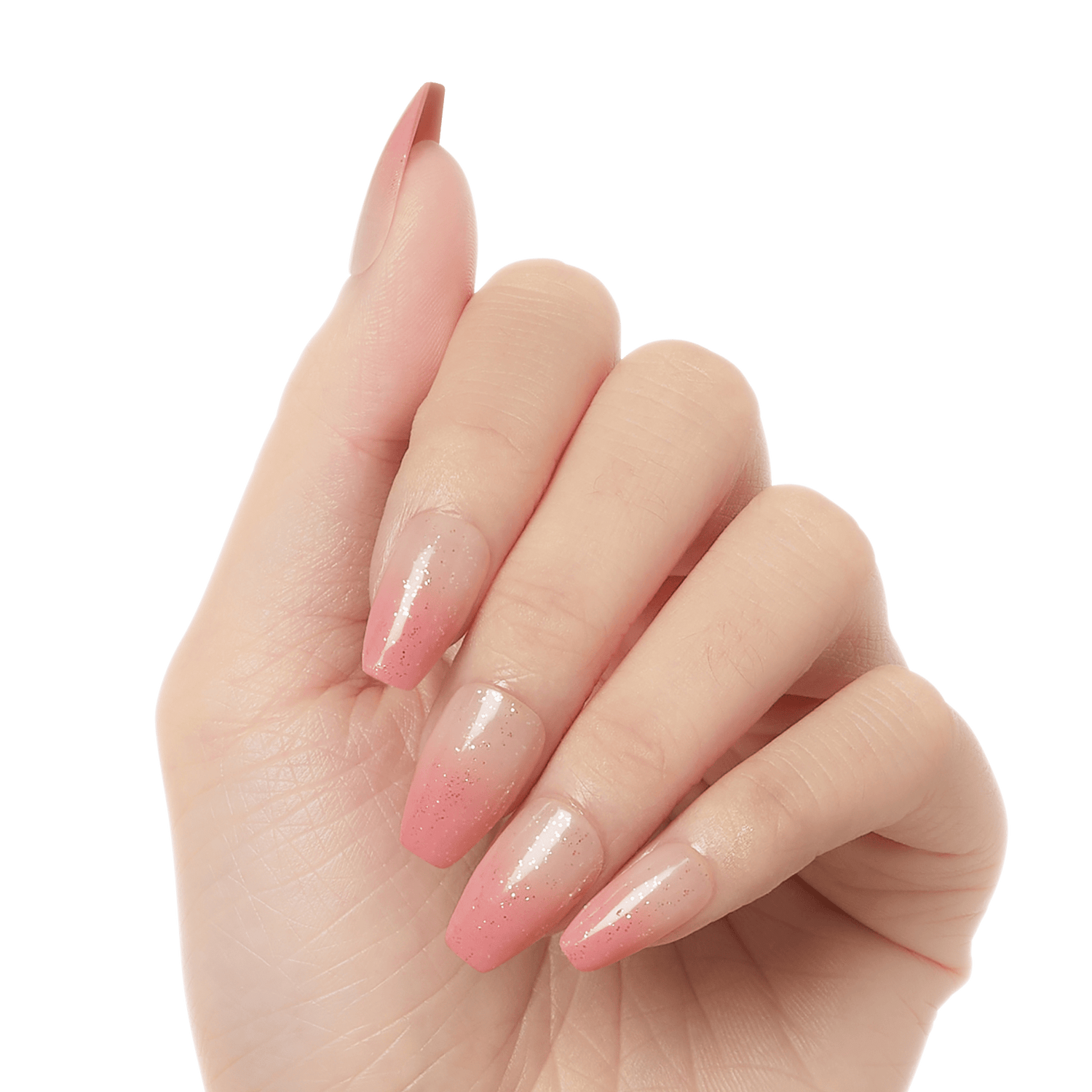 Hand showing five press-on gel nails with an ombre design fading from clear nude at the base to soft pink tips with subtle sparkles.
