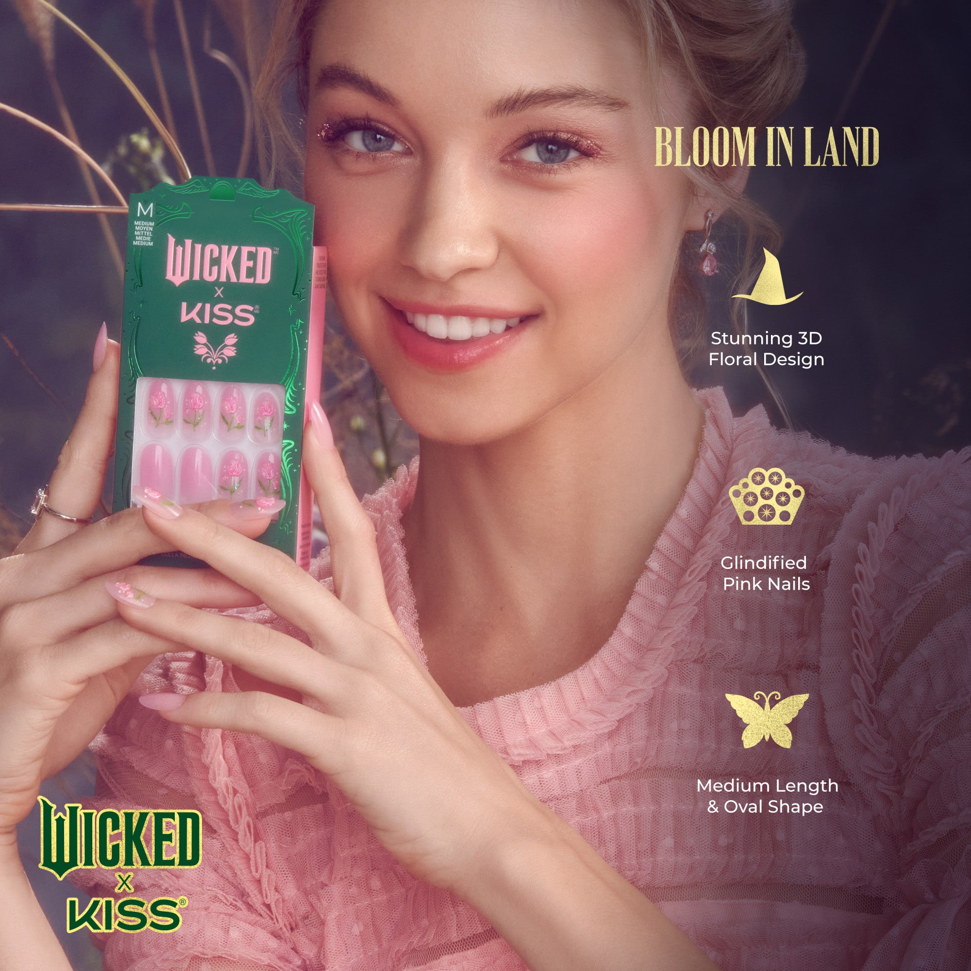 Smiling woman in pink blouse holding Wicked x Kiss Bloom in Land press-on nails with pink floral 3D design, medium length, oval shape, and glindified finish.