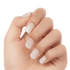 Hand with neatly manicured press-on nails in a natural, soft matte finish with a subtle beige-pink tint, nails shaped in a short square style.