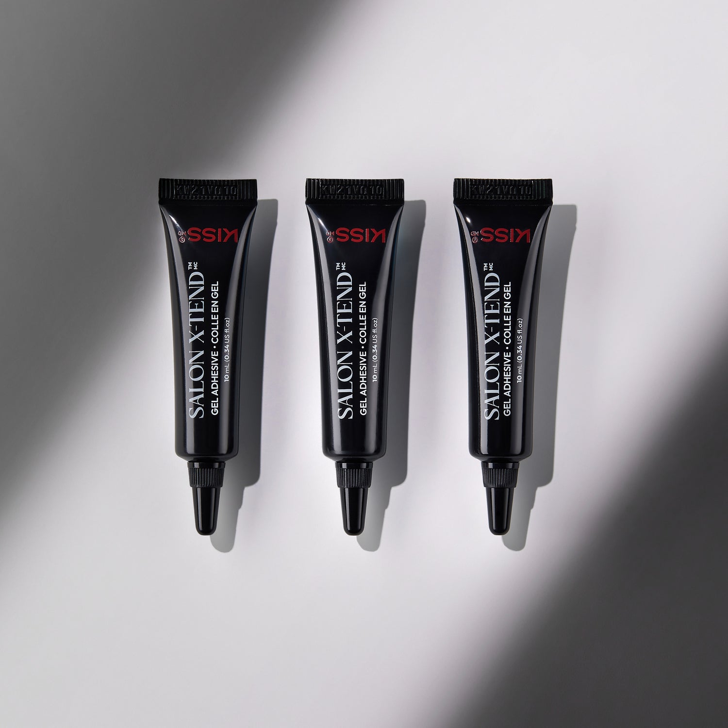 Three black tubes of KISS Salon X-tend LED Gel Adhesive, each labeled with product name and volume 10 mL (0.34 US fl oz), arranged vertically on a light gray background with soft shadow.
