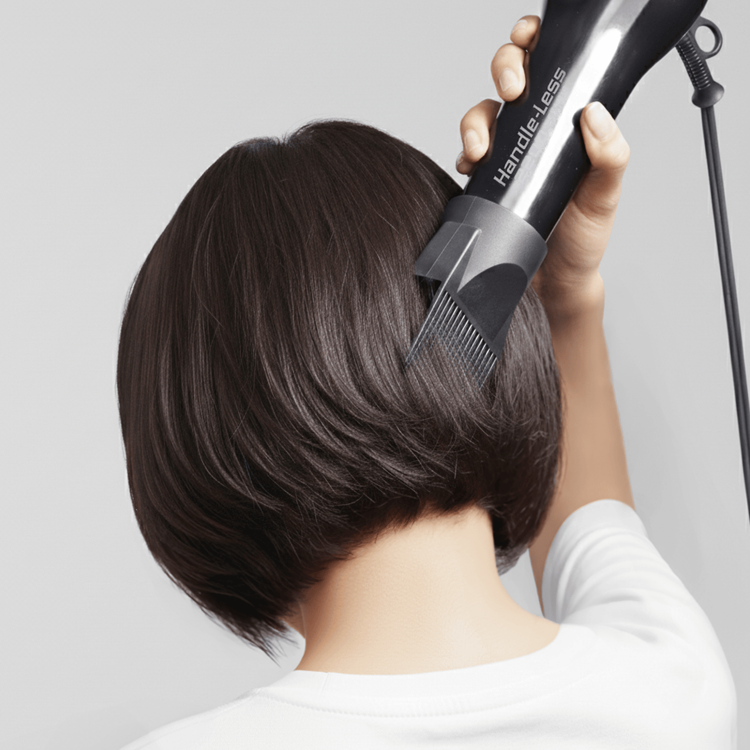 Back view of a person with short dark hair using a black Handle-Less 1875 ceramic tourmaline hair dryer with an attached comb attachment.