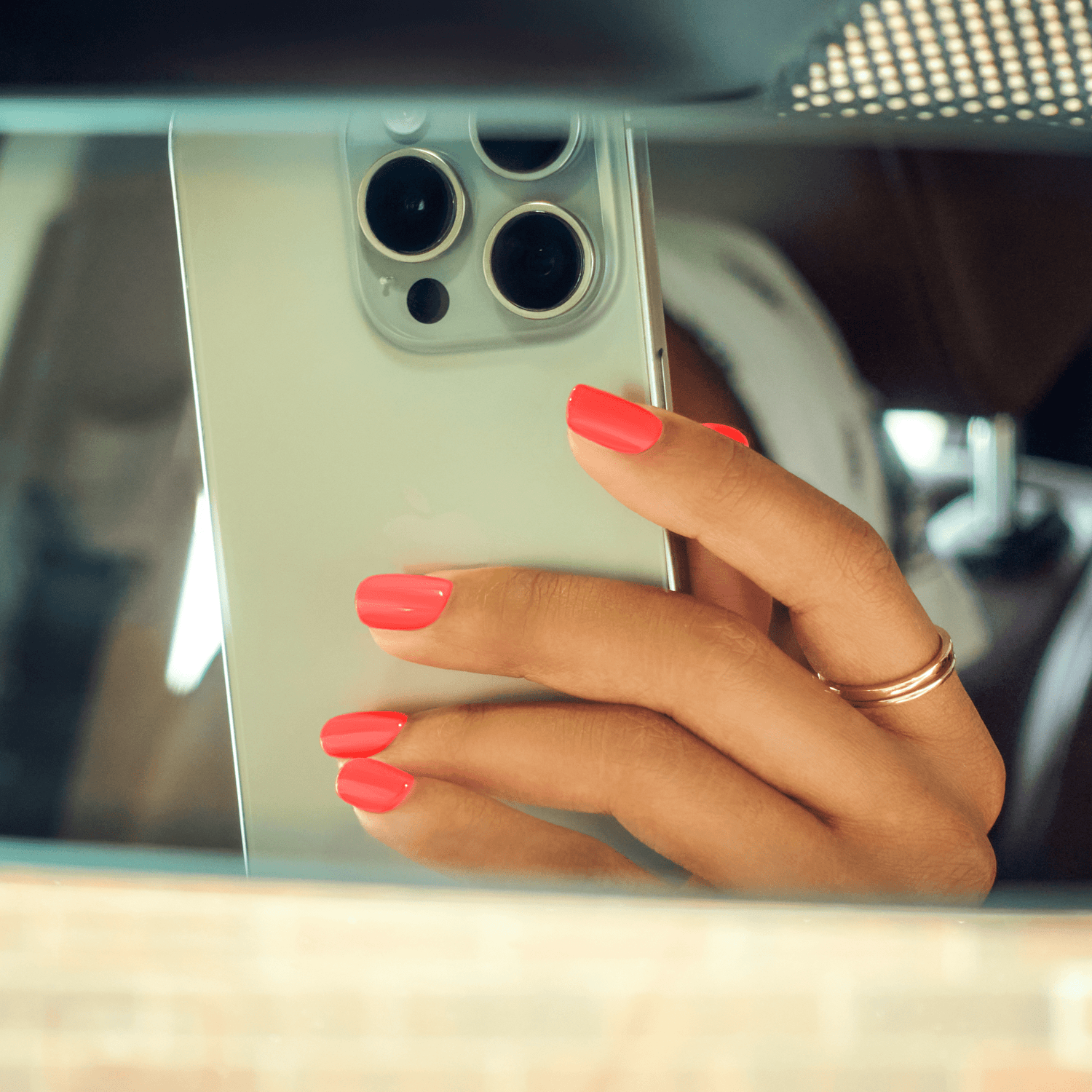 Person with red nail polish holding silver iPhone 14 Pro Max