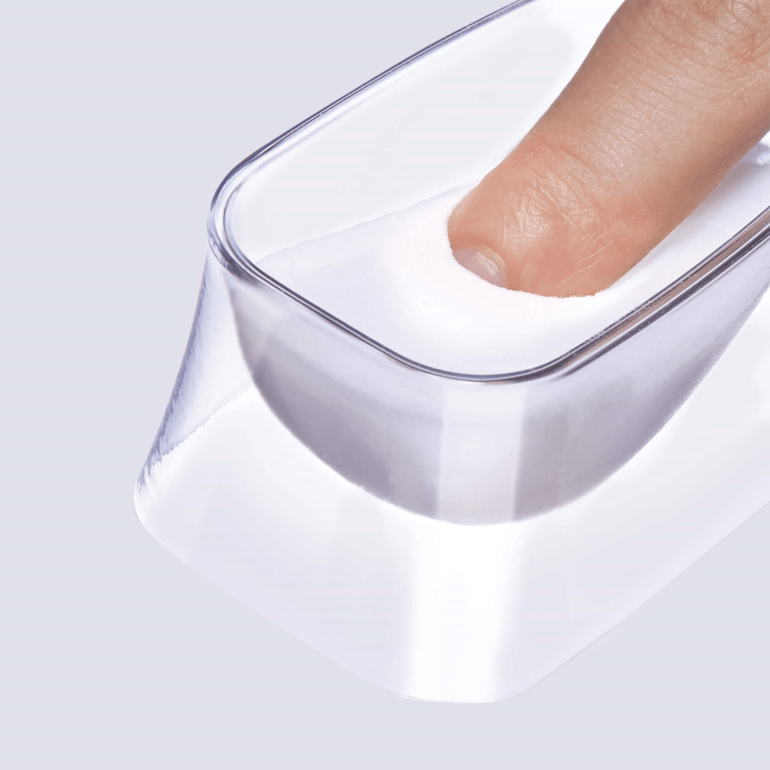 Fingertip dipped into a clear rectangular container filled with fine white powder from the KISS Salon Dip Professional Dipping System.