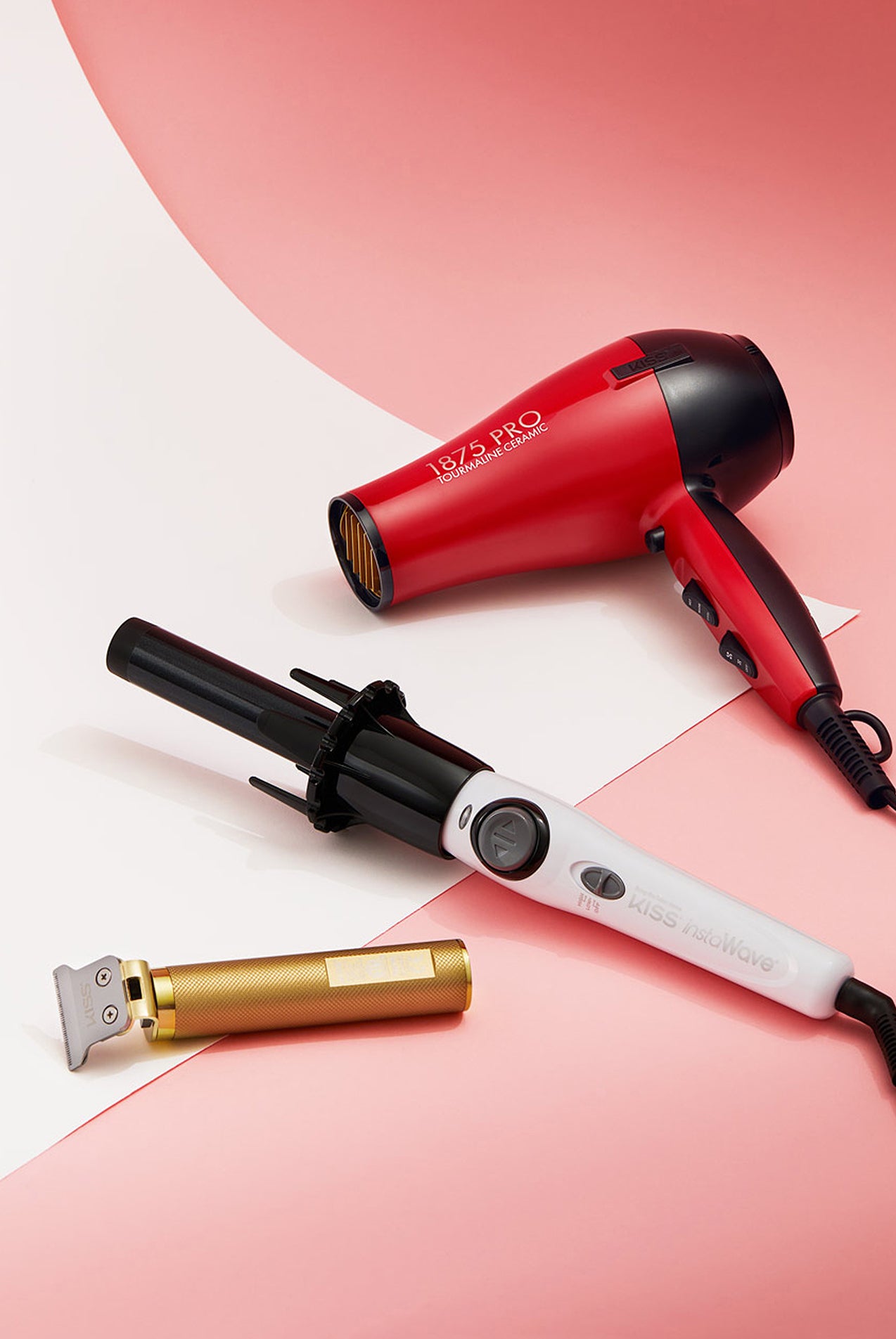 Three hair styling tools on pink background: red 1&2&3 Pro hair dryer, white Kiss waveroller, and gold trimmer.