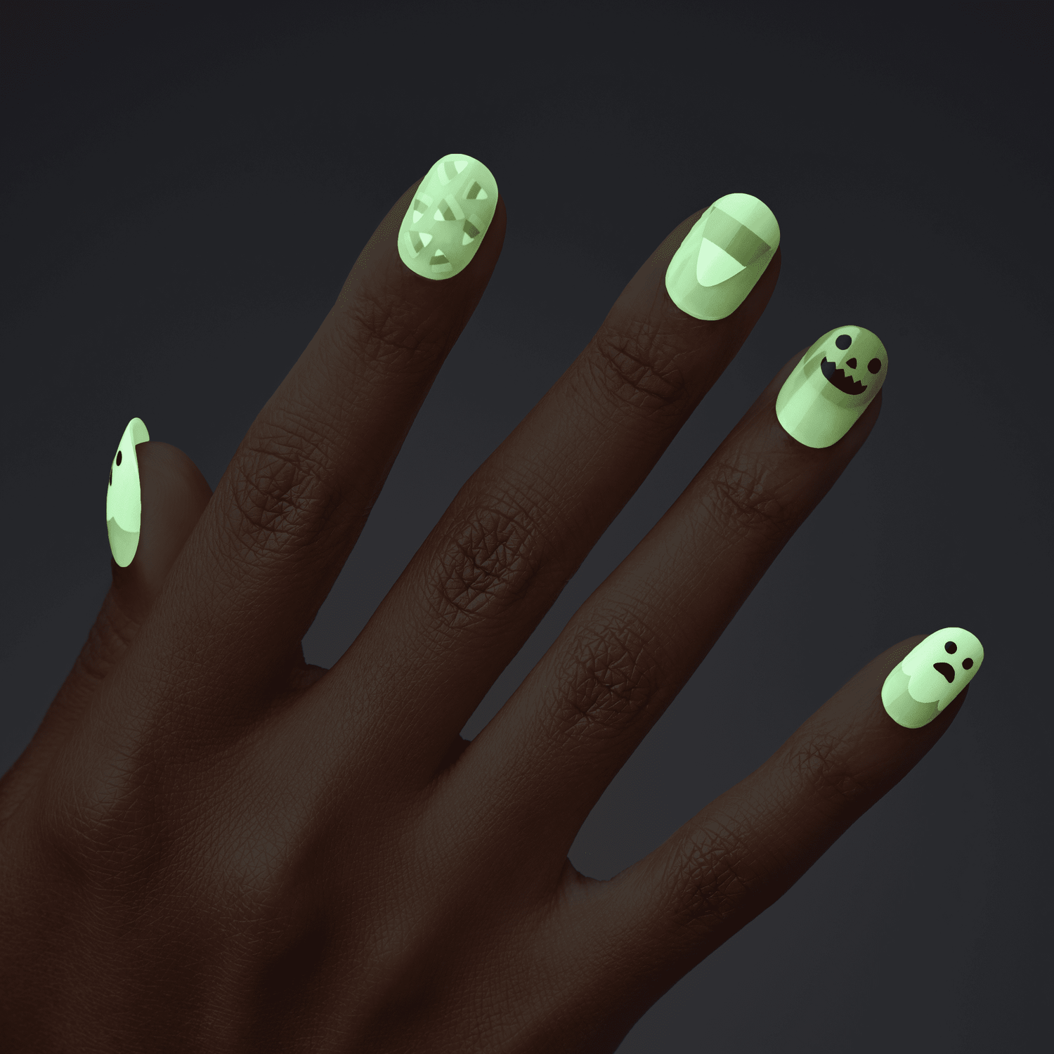 Dark-skinned hand with glow-in-the-dark press-on nails featuring spooky Halloween designs: mummy wraps, a vampire mouth, a jack-o&
