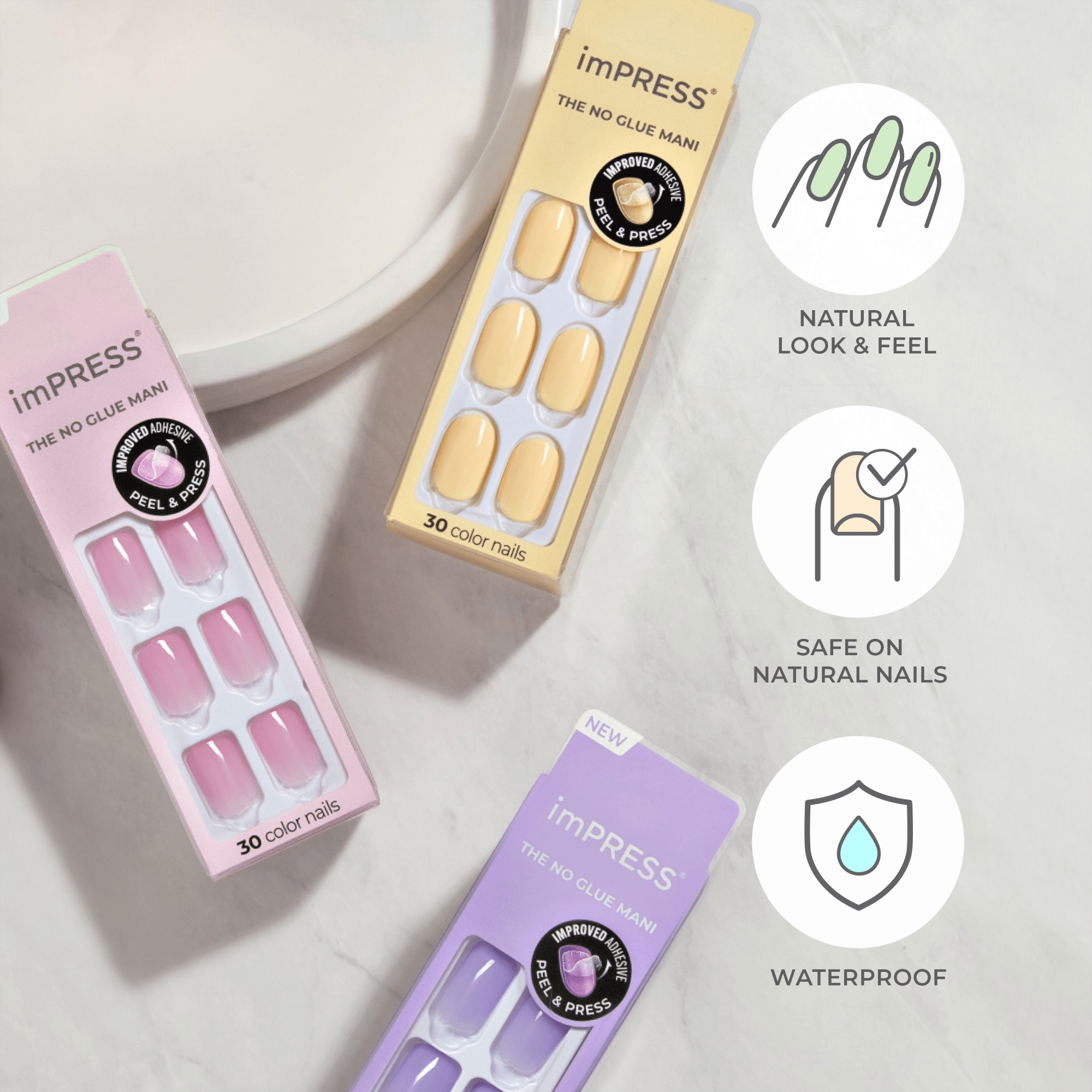 Three packages of imPRESS press-on nails in pastel pink, yellow, and lavender hues on a marble surface. Each package contains 30 color nails and highlights \