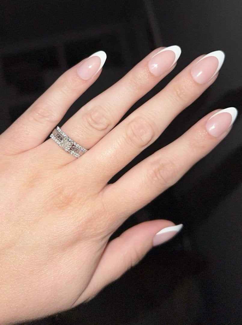 Classic French manicure with white tips on almond nails and diamond ring.