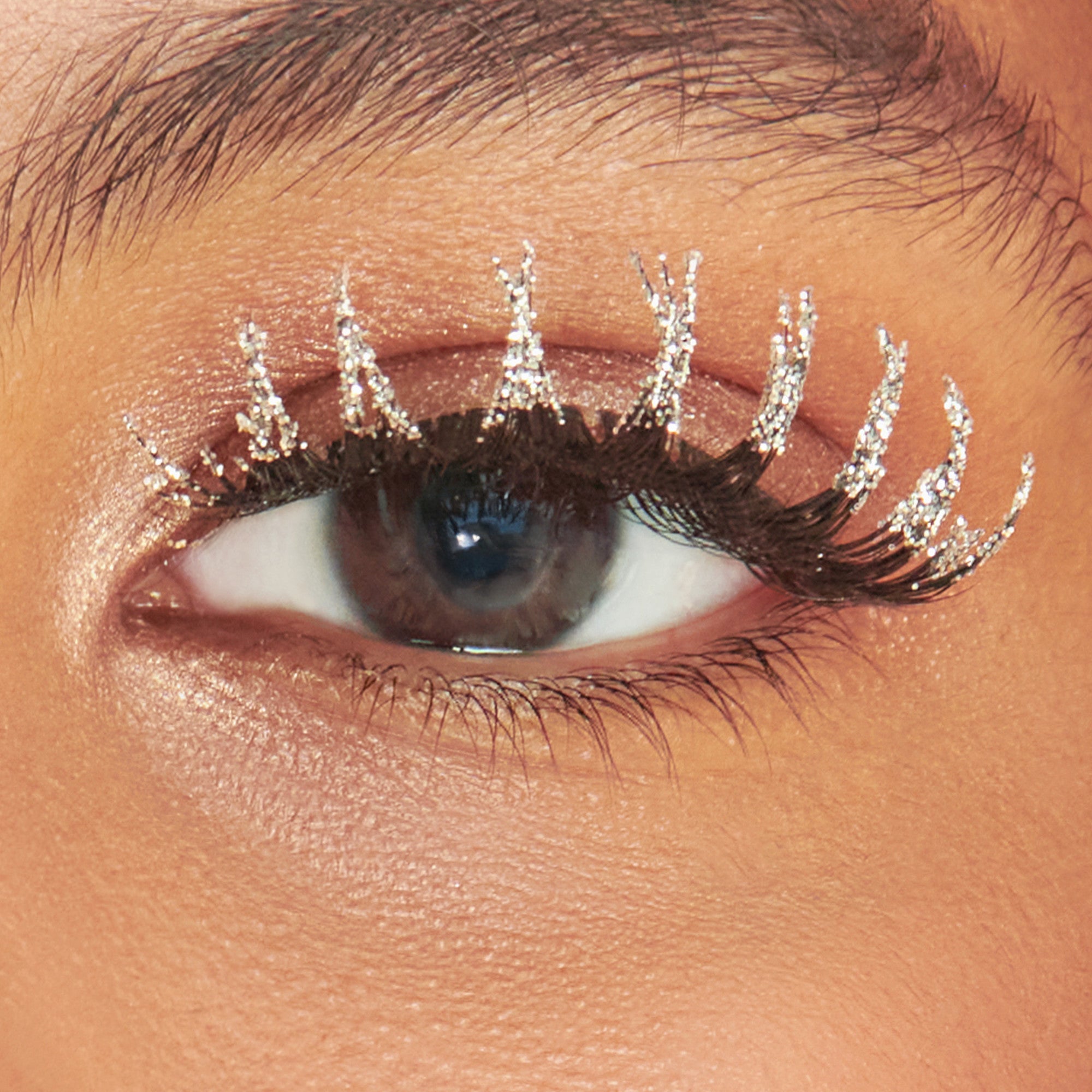 Close-up of eye with sparkly crystal-embellished false lashes and shimmery eyeshadow.
