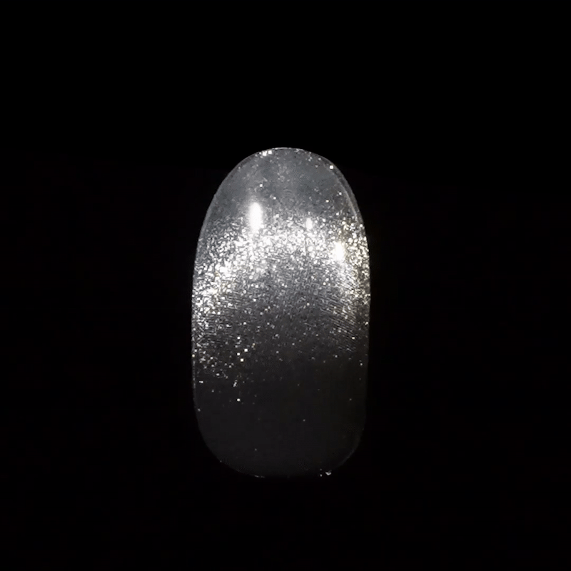 Glossy press-on nail with a gradient silver glitter design, shown against a black background, highlighting a sparkling, elegant finish.