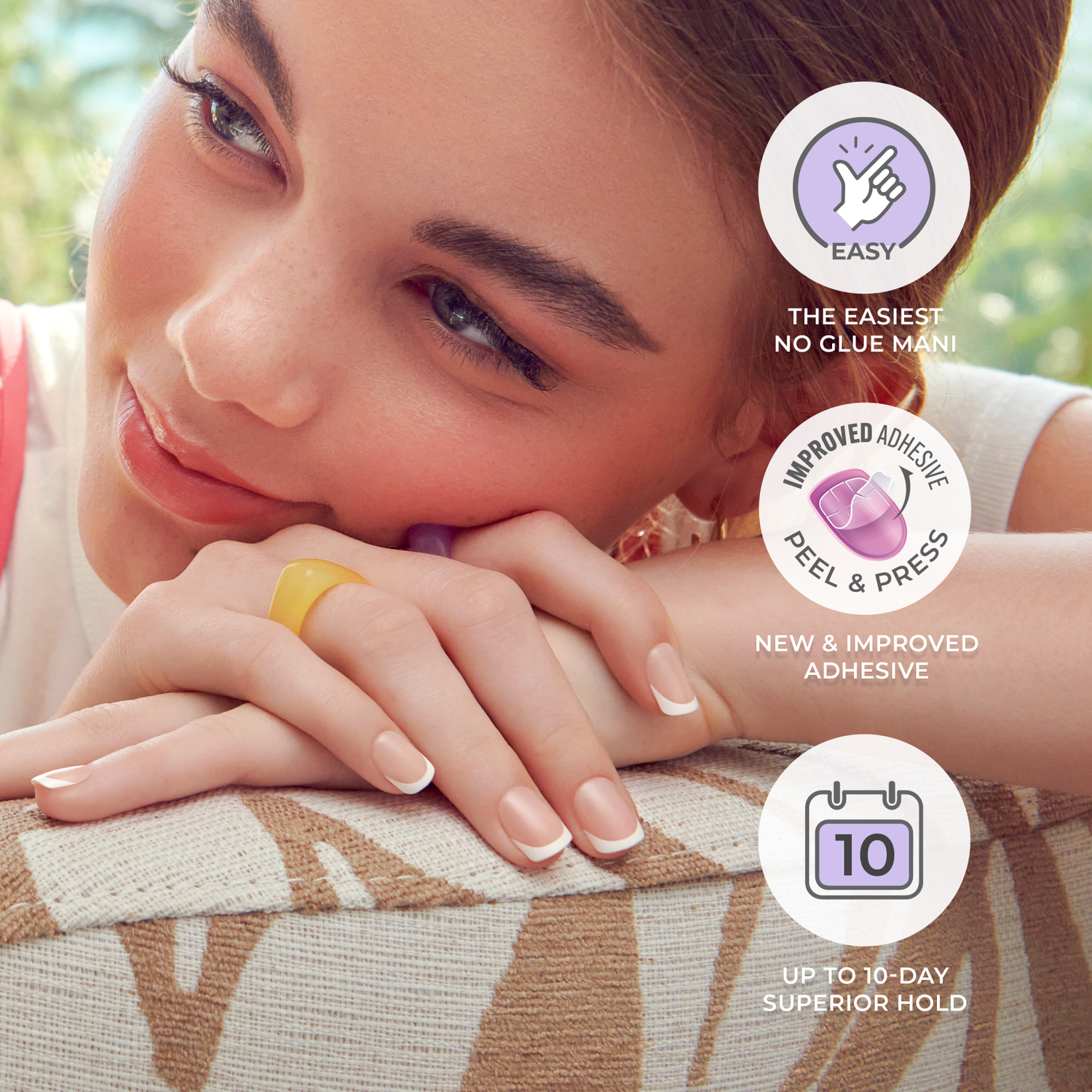 Young woman resting her hands on patterned fabric, showcasing natural-looking press-on nails with white French tips. Text highlights easy no-glue application, new improved adhesive, and up to 10-day superior hold.