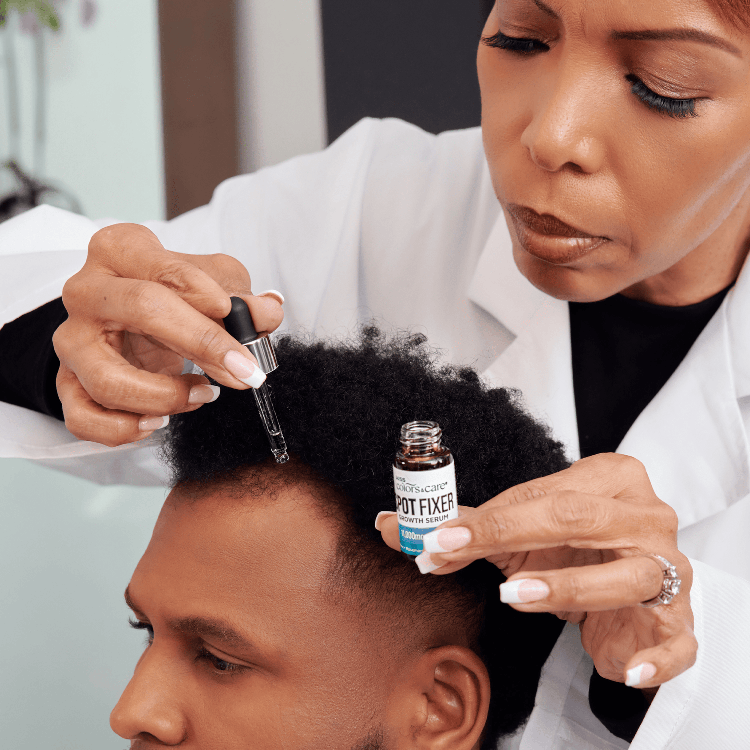 Woman in a white coat applies Kiss Colors Care Spot Fixer Growth Serum with a dropper to a man&