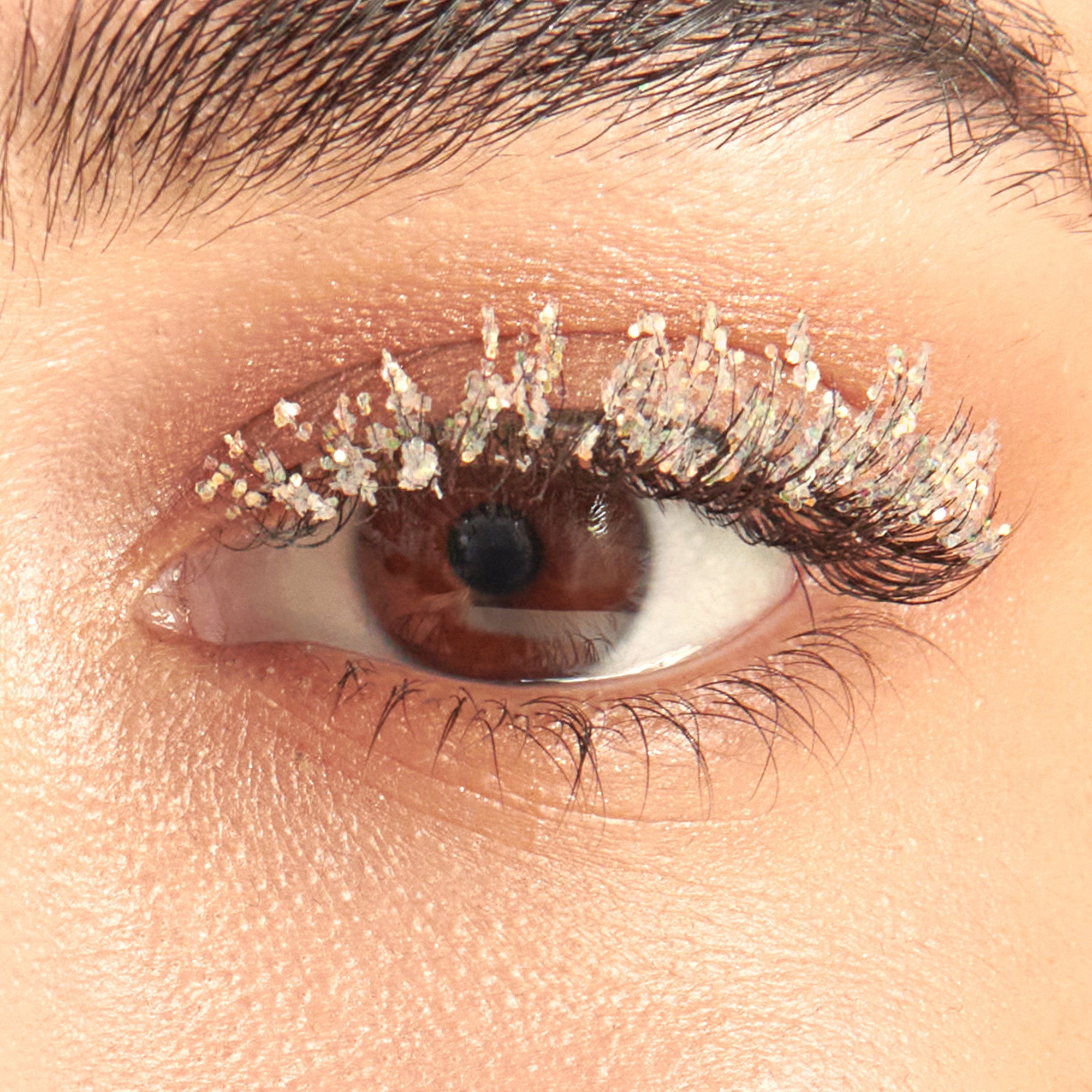 Close-up of eye with glittery gold eyeshadow on upper lid and dark eyeliner.