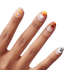 Hand with Halloween-themed press-on nails showing candy corn, a large candy corn tip, a jack-o&