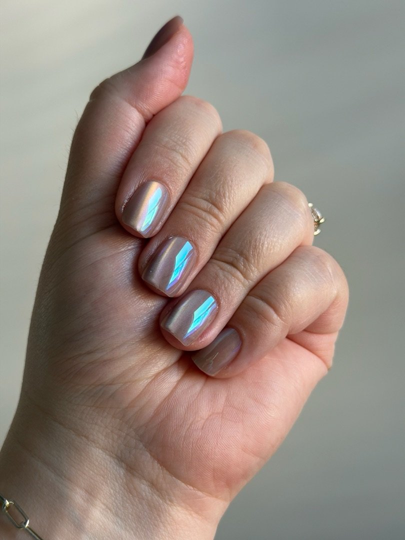 Hand displaying short nude nails with holographic chrome stripe accents