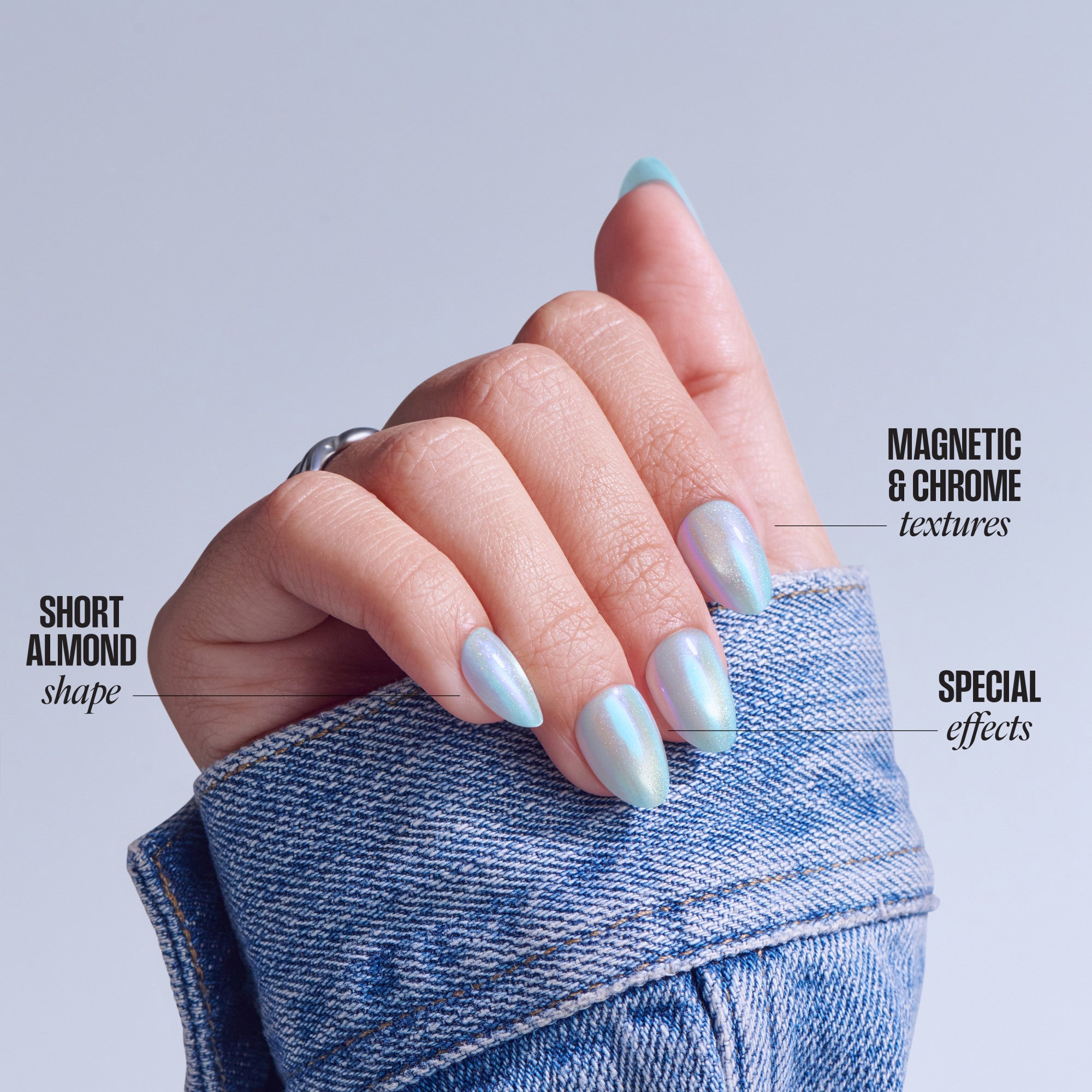Short almond nails with magnetic chrome and iridescent textures on hand in denim sleeve.