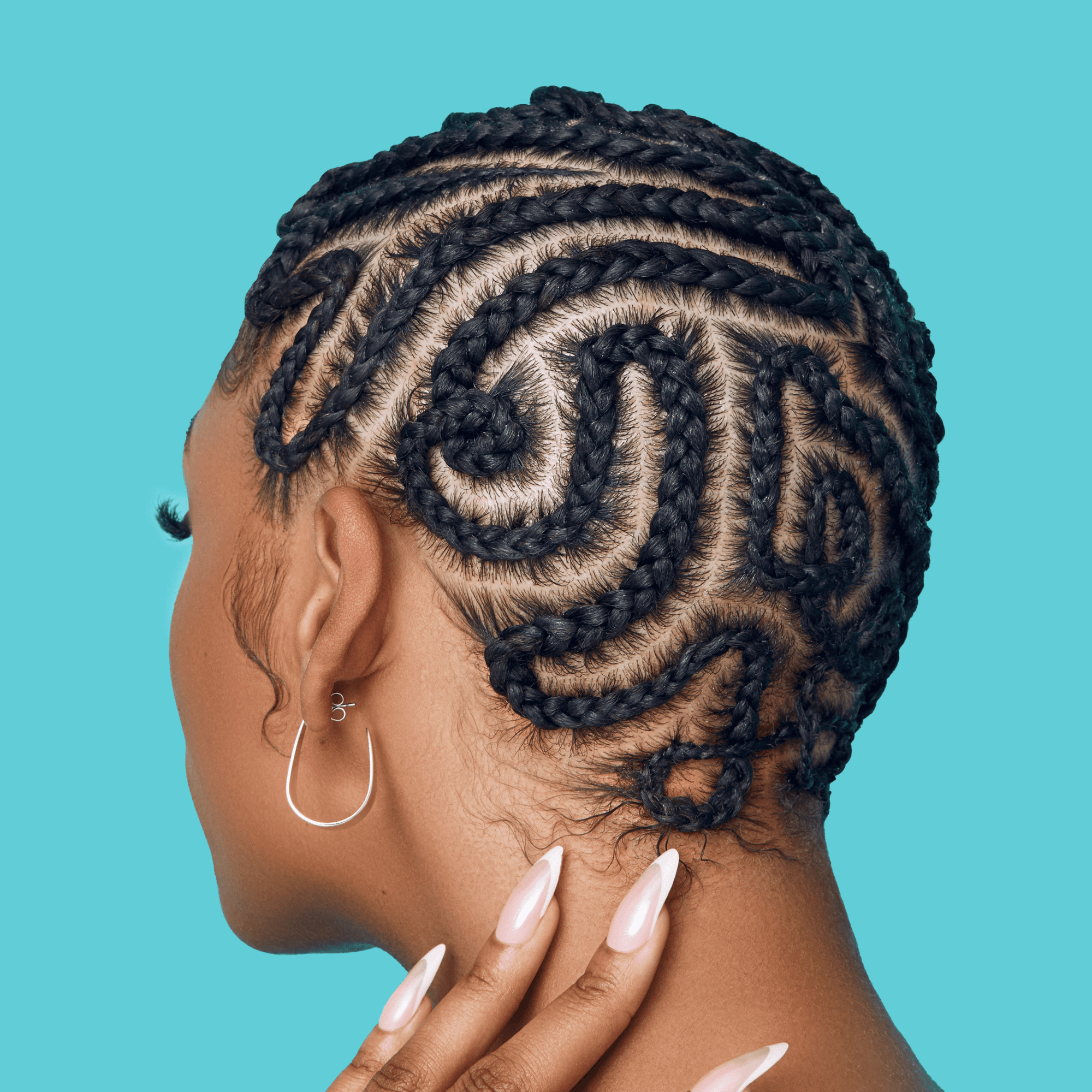 Woman with detailed black cornrow braids styled in a swirl pattern on a bright turquoise background, showing silver hoop earring and hand with long pale pink nails gently touching neck.