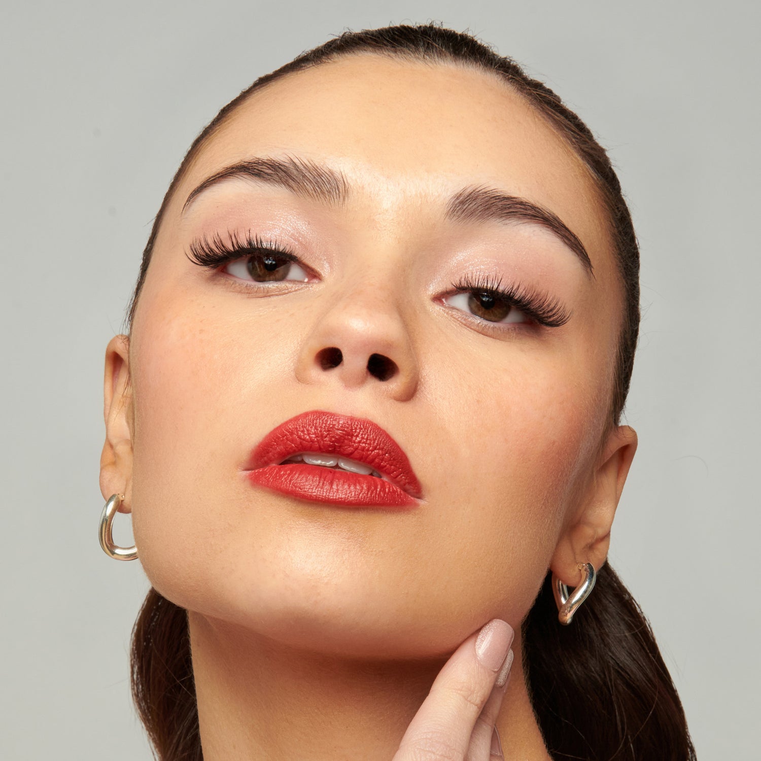 Close-up of a woman with red lipstick and a neutral background