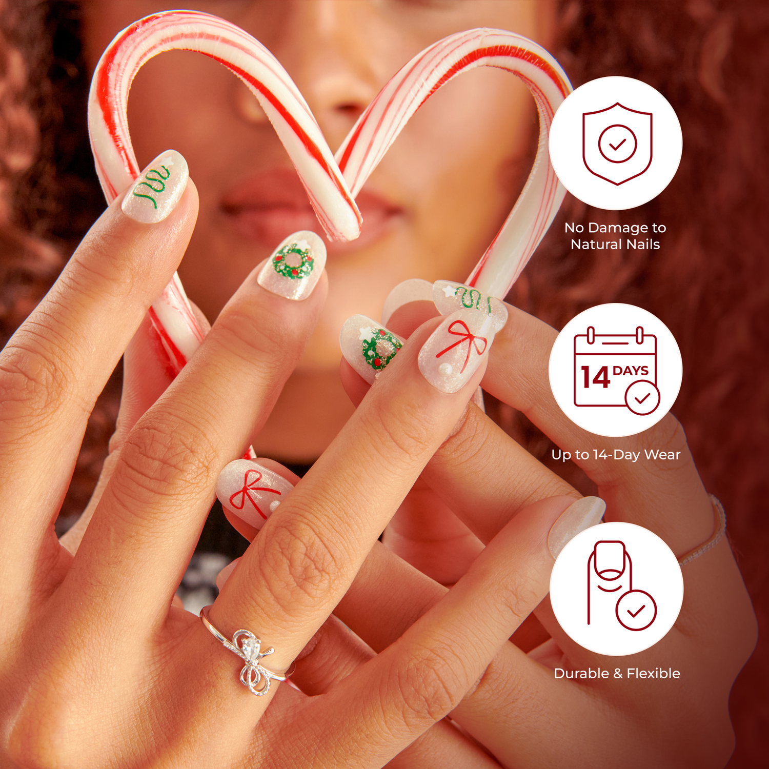 Hands with festive holiday press-on nails holding two candy canes shaped into a heart. Nails have white shimmer background with green wreaths, red bows, and green swirl designs. On-image text highlights \