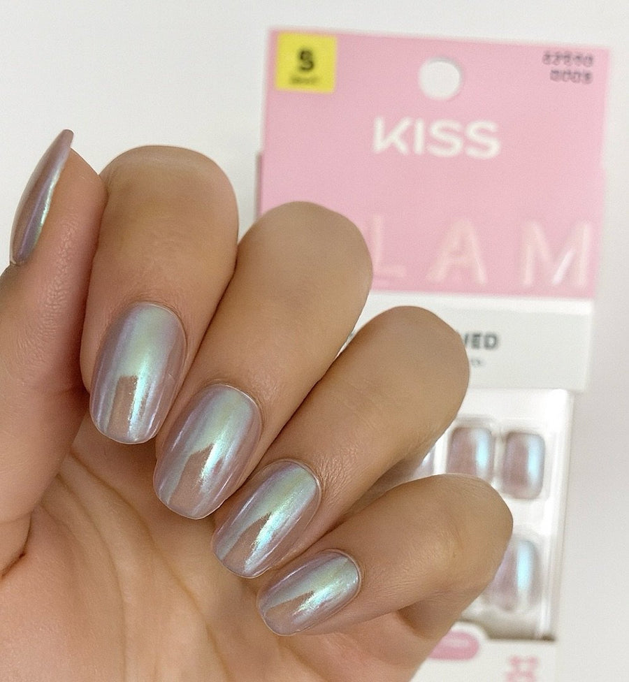 Hand displaying iridescent KISS press-on nails with pink packaging in background.