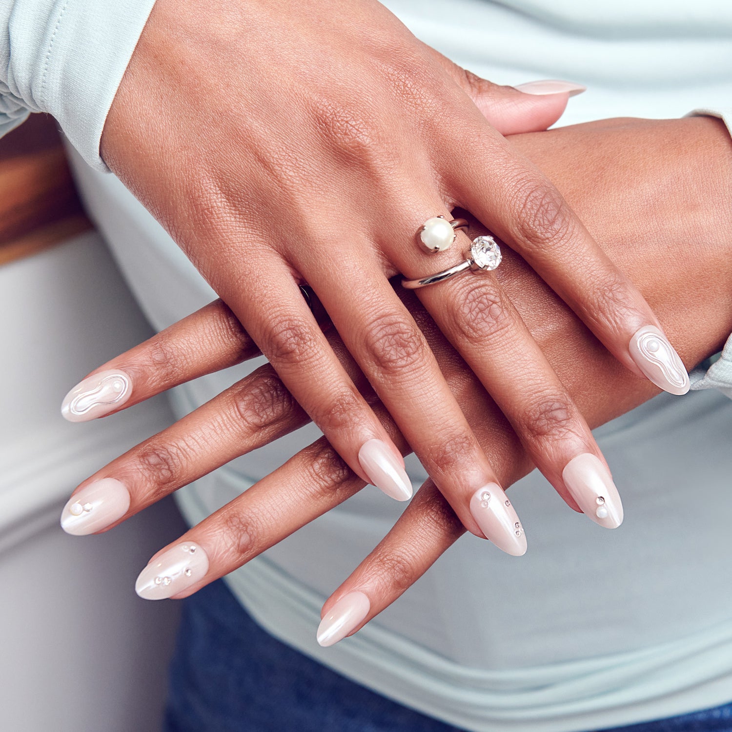 Manicured hands with pearl and diamond ring on white background